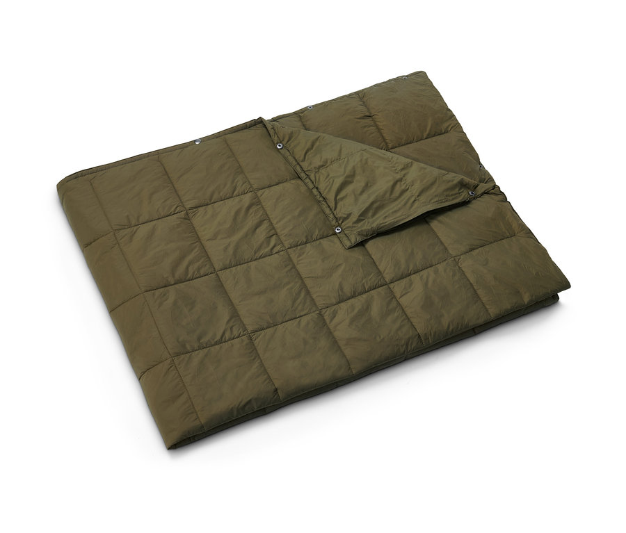 Une couverture de voyage ultralégère kaki matelassée est posée.