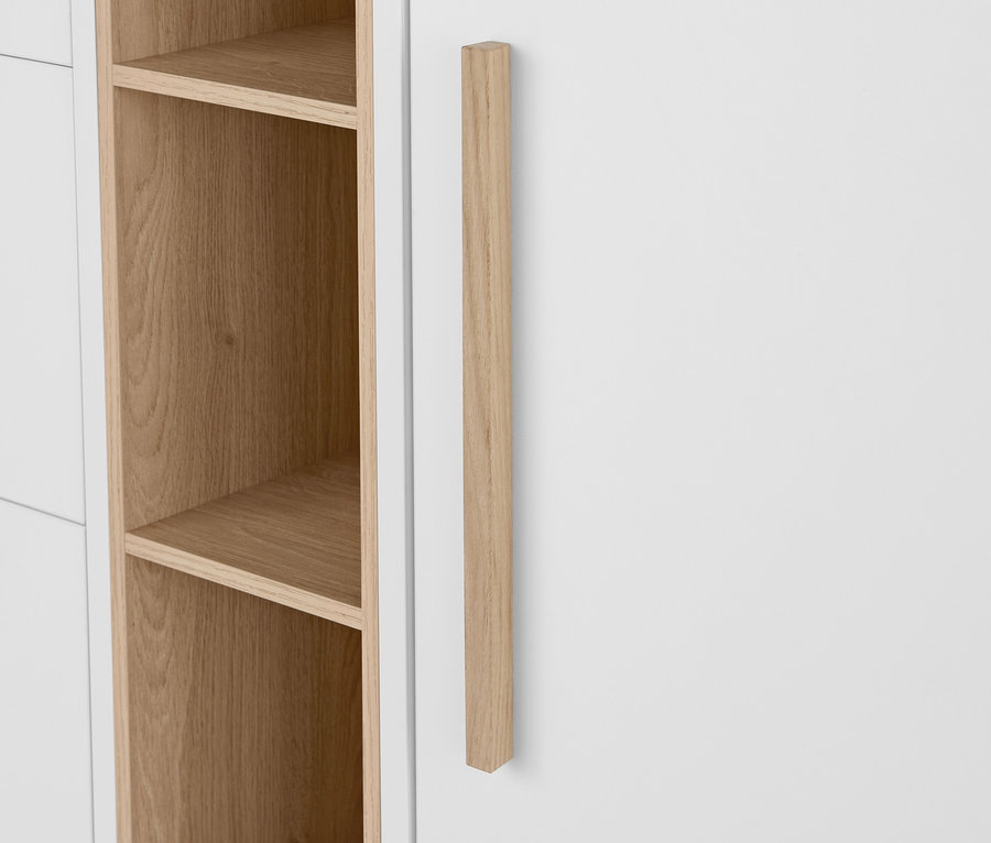 Détail d'une commode blanche « Eklund » avec tiroirs et porte, avec poignée en bois et étagères ouvertes.