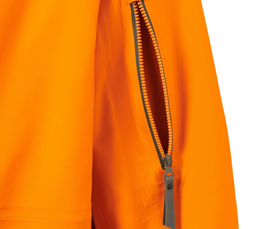 Détail d'une veste de ski hardshell orange avec une fermeture éclair de poche ouverte.
