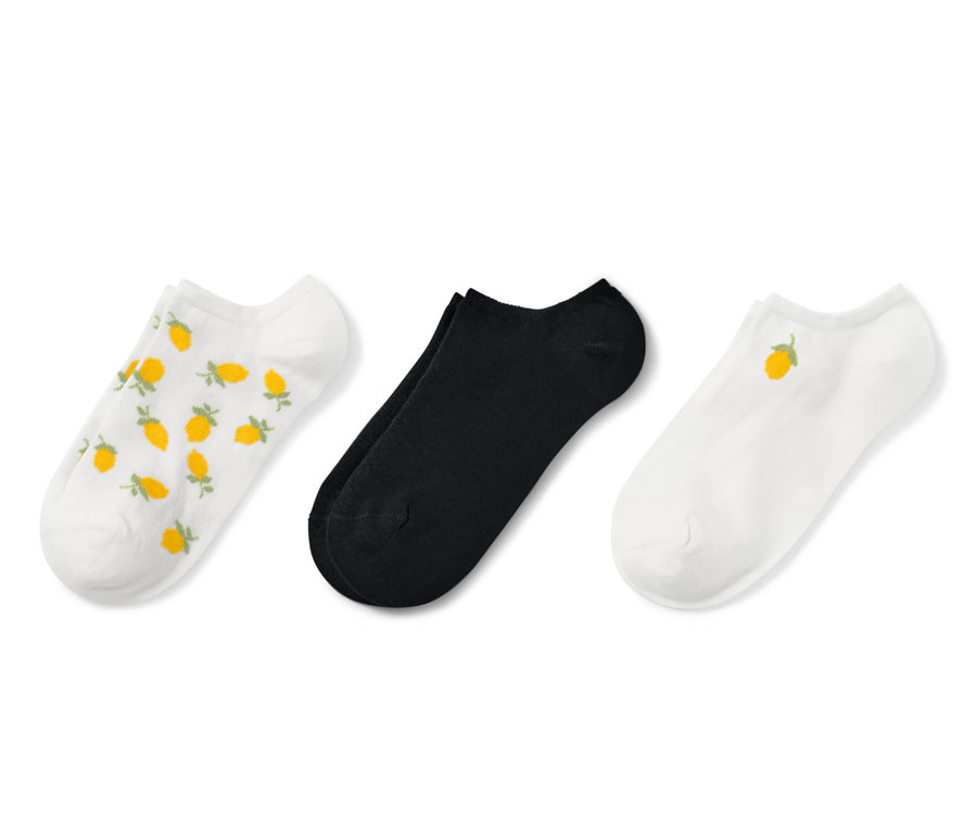 Trois paires de socquettes de sport sont visibles. Une paire est blanche avec des citrons jaunes imprimés, une paire est noire et une paire est blanche avec un seul citron jaune.