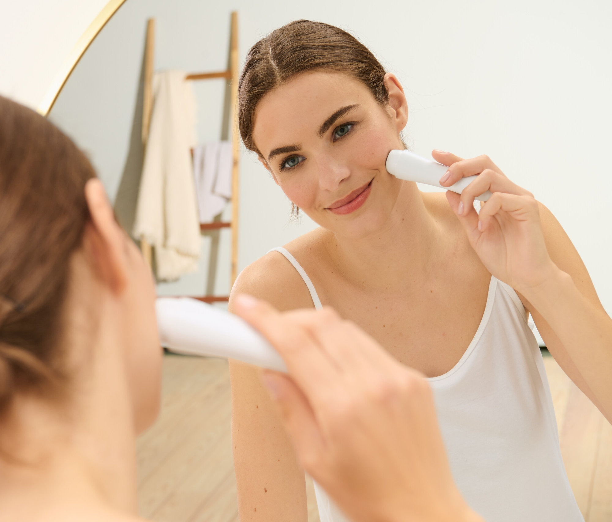 Une femme utilise un épilateur électrique pour le visage devant un miroir.