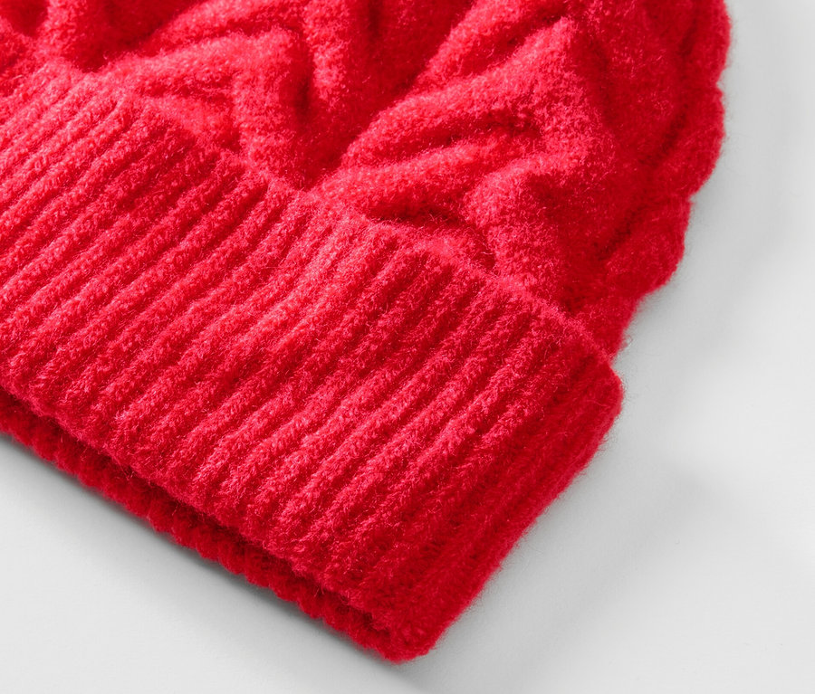 Gros plan d'un bonnet en maille rouge à motif torsadé.