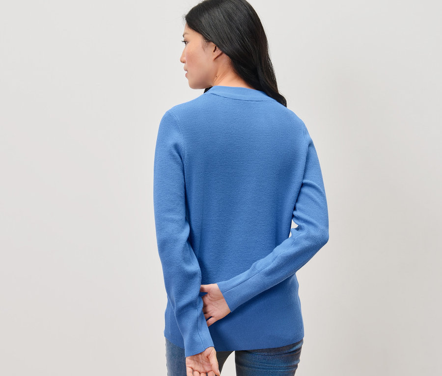 Une femme, vue de dos, porte un pull bleu en maille fine.