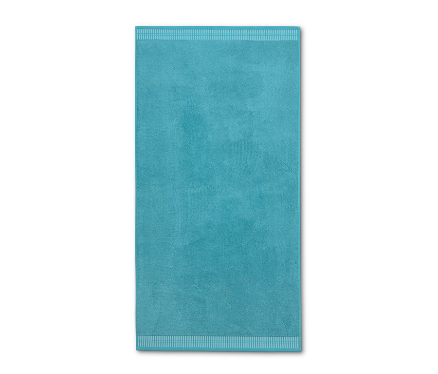 Un drap de bain premium turquoise est posé sur un fond blanc.