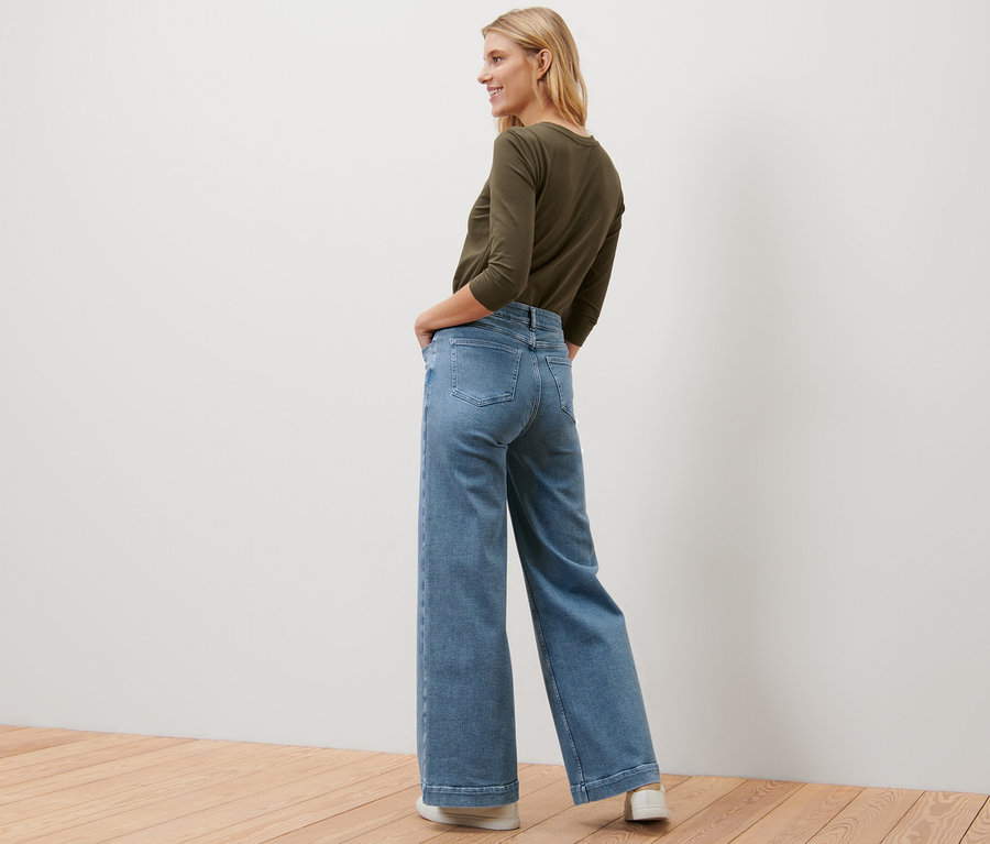 Une femme blonde pose en jeans Wide Leg – Fit « Viki » et haut olive.