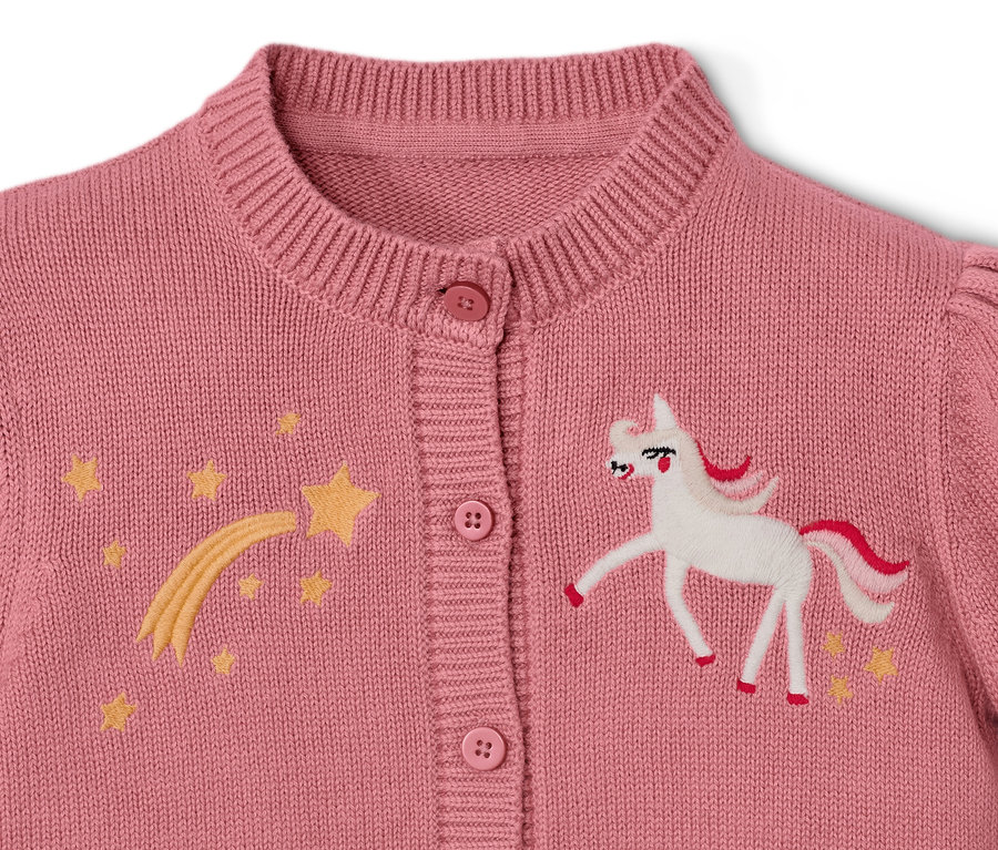 Détail d'une jaquette en maille pour enfant avec une licorne et des étoiles.