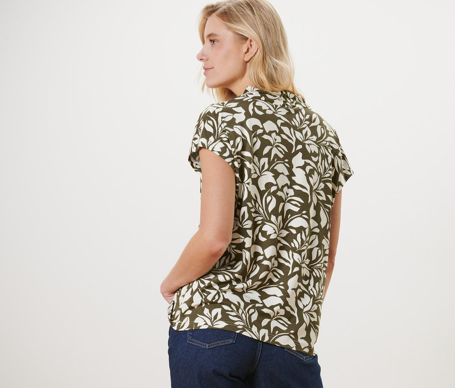 Une femme, vue de dos, porte une blouse imprimée avec encolure en V et un jean.