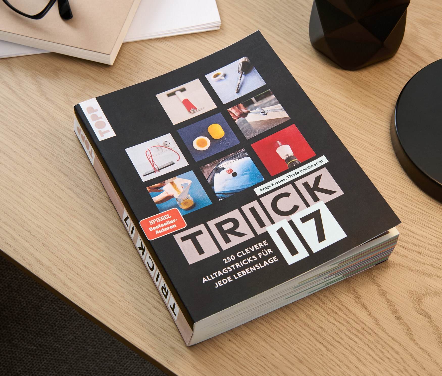 Le livre « Trick 17 » est posé sur une table à côté de lunettes, d'un bloc-notes et d'un pot à crayons.