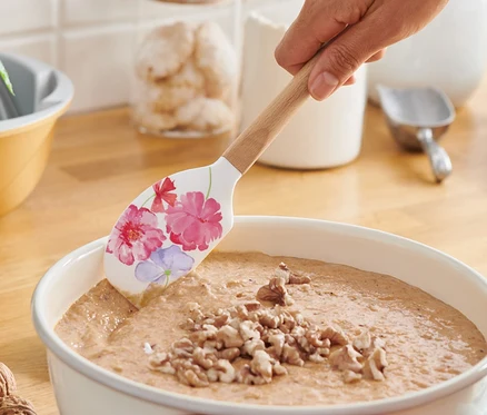 Une femme mélange de la pâte avec une spatule.