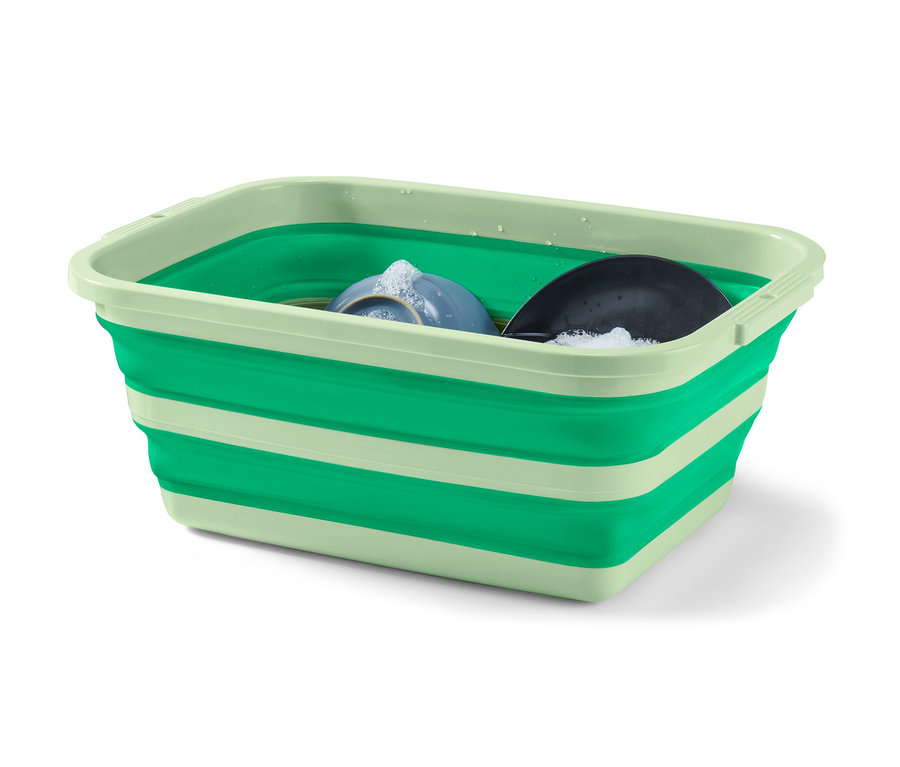 De la vaisselle sale se trouve dans un panier à linge et à vaisselle pliable vert.