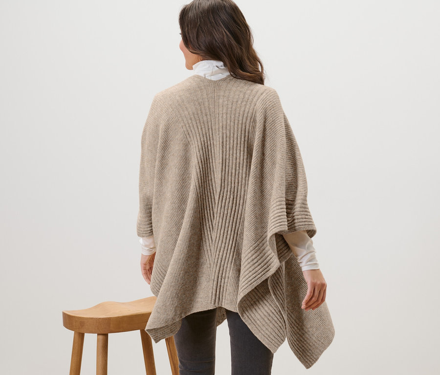 Femme vue de dos portant une cape en tricot.