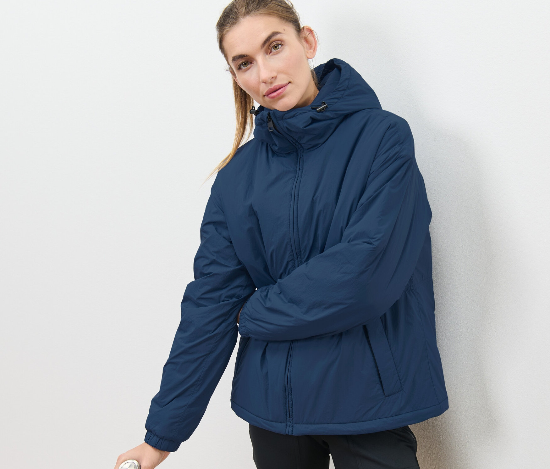 Femme posant en veste à capuche et tenant une bouteille d'eau.