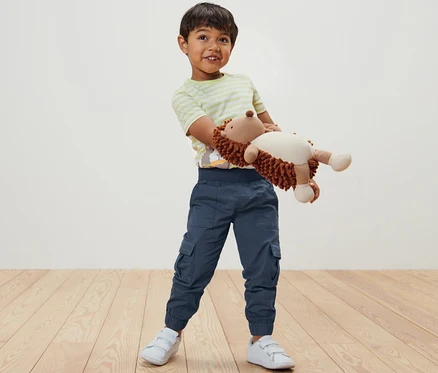 Garçon tenant un hérisson en peluche et portant un pantalon à enfiler pour enfant – Fit « Anton ».