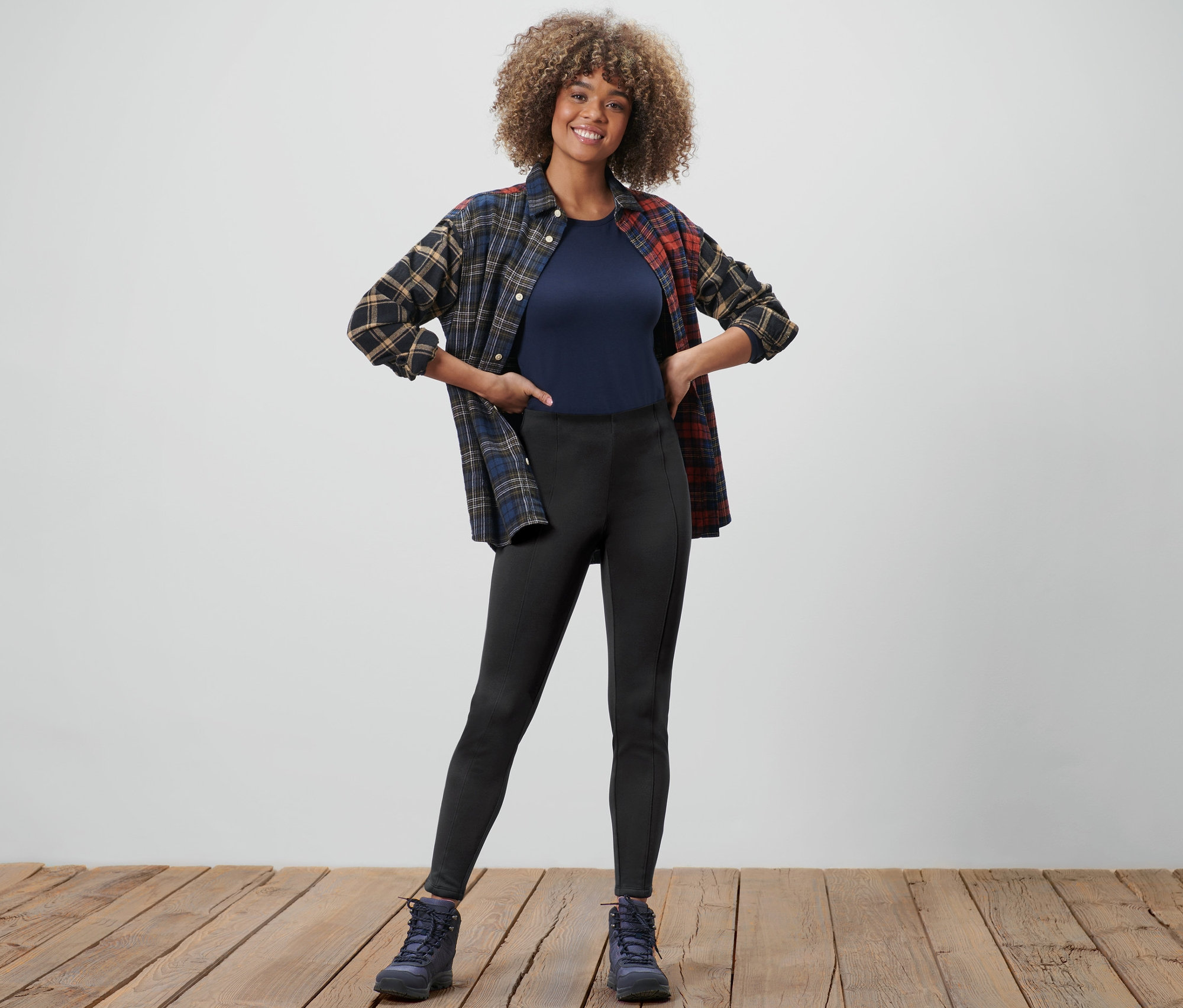 Femme posant en legging thermique, t-shirt et chemise en flanelle.