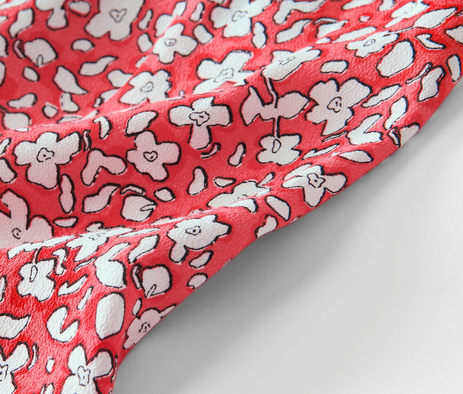 Détail d'une jupe midi corail imprimée.