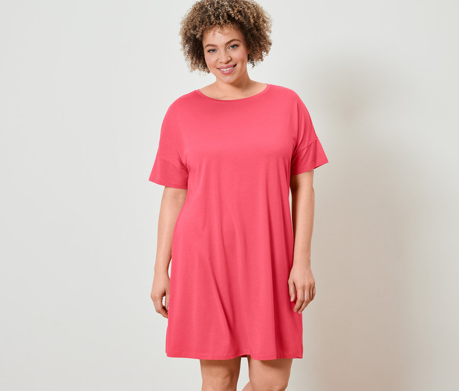 Femme aux cheveux bouclés posant en chemise de nuit.