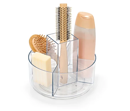 Un récipient transparent rotatif contenant du savon, une brosse à cheveux et un flacon de shampoing.