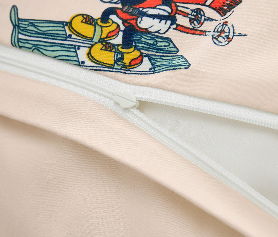 Gros plan sur une housse de couette avec un imprimé de Mickey Mouse faisant du ski et une fermeture éclair partiellement ouverte.