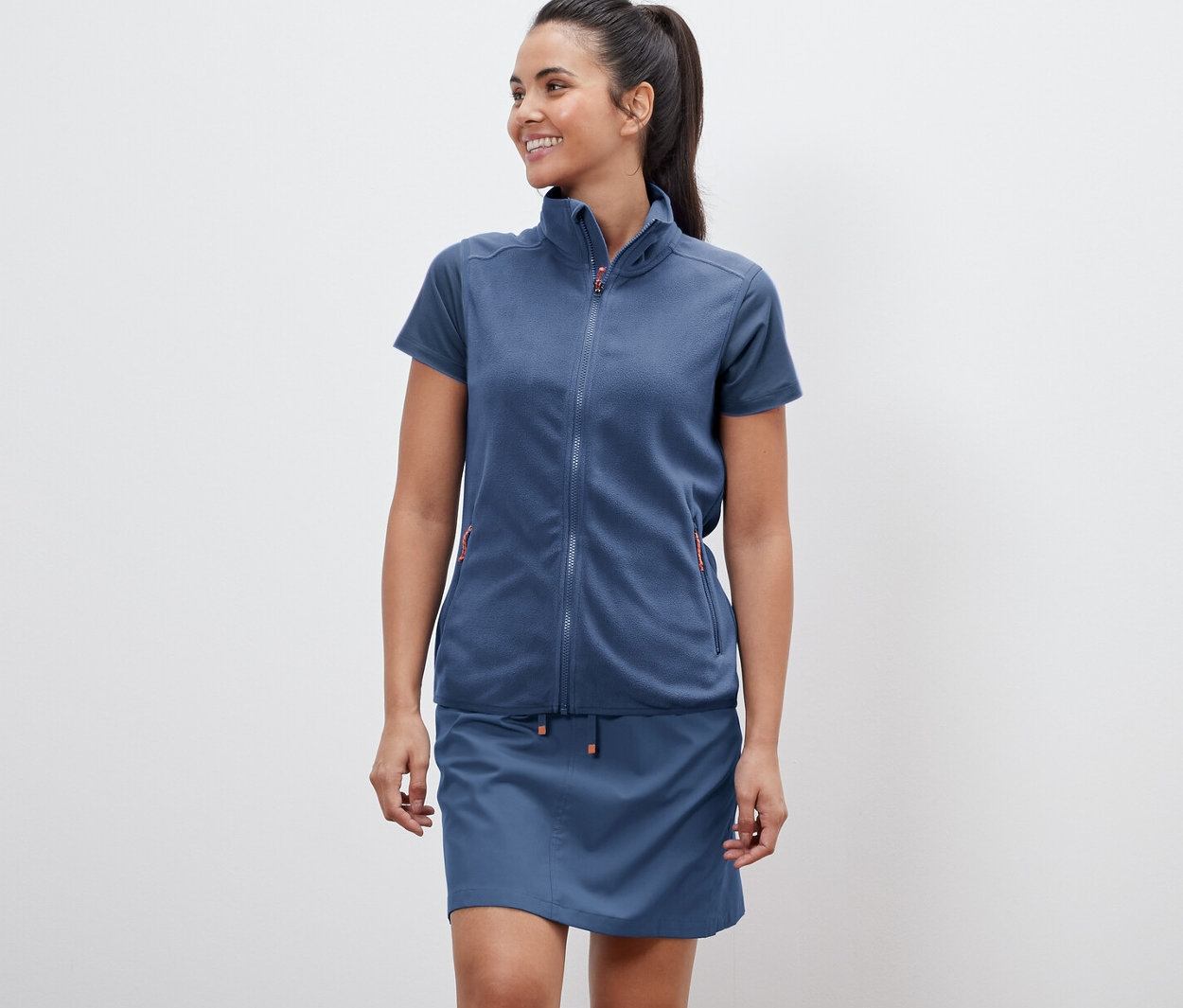 Femme portant un gilet sans manches en polaire et une jupe.