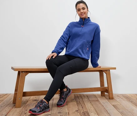 Une femme est assise sur un banc et porte un pull en polaire bleu.