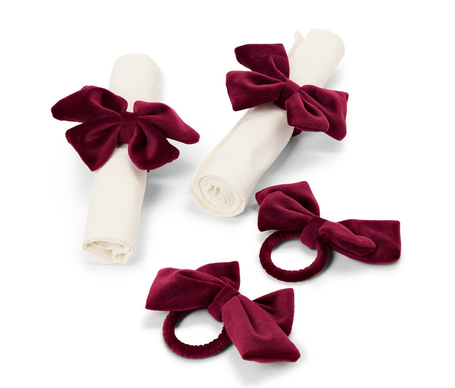 Deux serviettes enroulées et maintenues par des nœuds en velours bordeaux, et deux ronds de serviette individuels ornés de nœuds bordeaux.