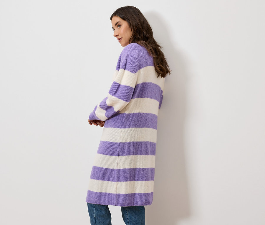 Femme posant dans un long cardigan rayé violet et crème.