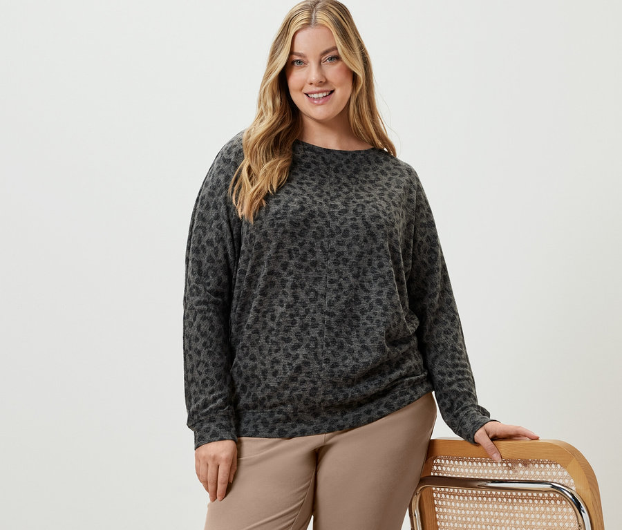 Femme posant en pantalon de jogging beige et t-shirt chauve-souris imprimé.