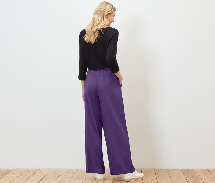 Femme vue de dos portant un pantalon palazzo structuré violet.