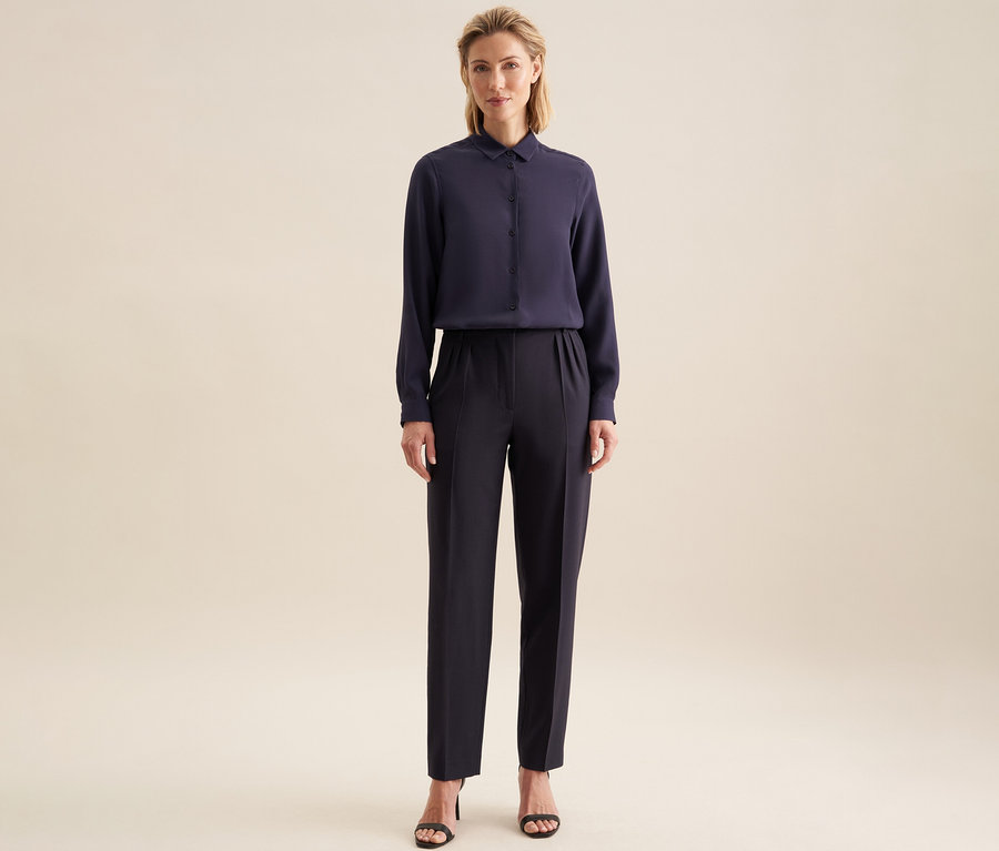 Femme portant un chemisier en viscose Seidensticker bleu foncé, un pantalon bleu foncé et des sandales noires.