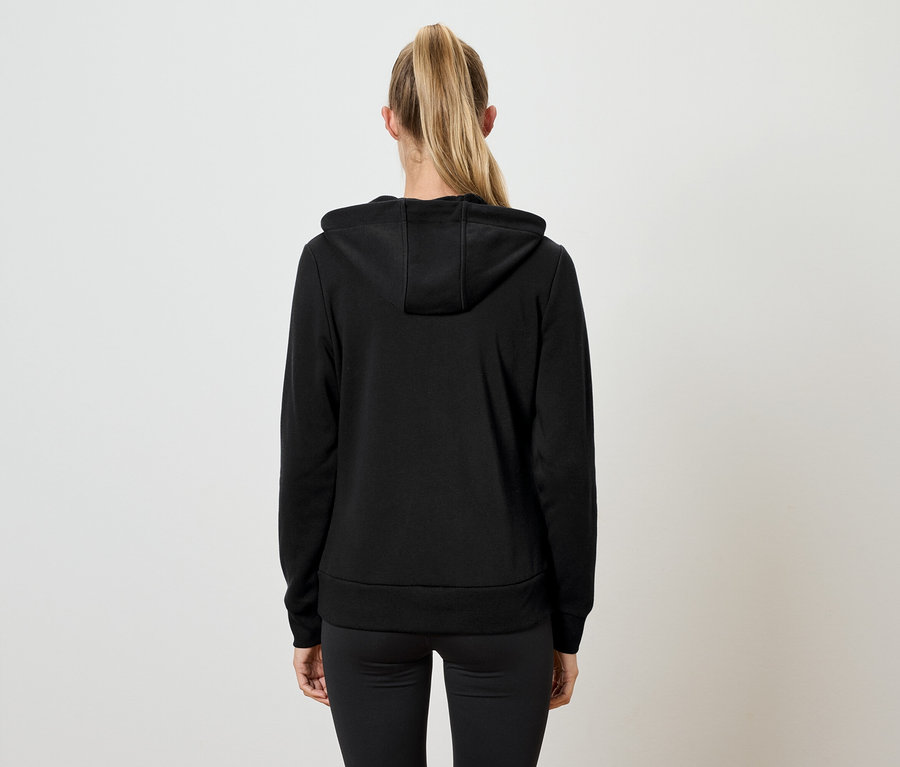 Vue de dos d'une femme aux cheveux blonds attachés en queue de cheval portant un sweat à capuche noir et un pantalon noir.