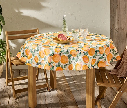 Nappe lavable ronde à imprimé d'agrumes sur une table avec des verres et des fruits.