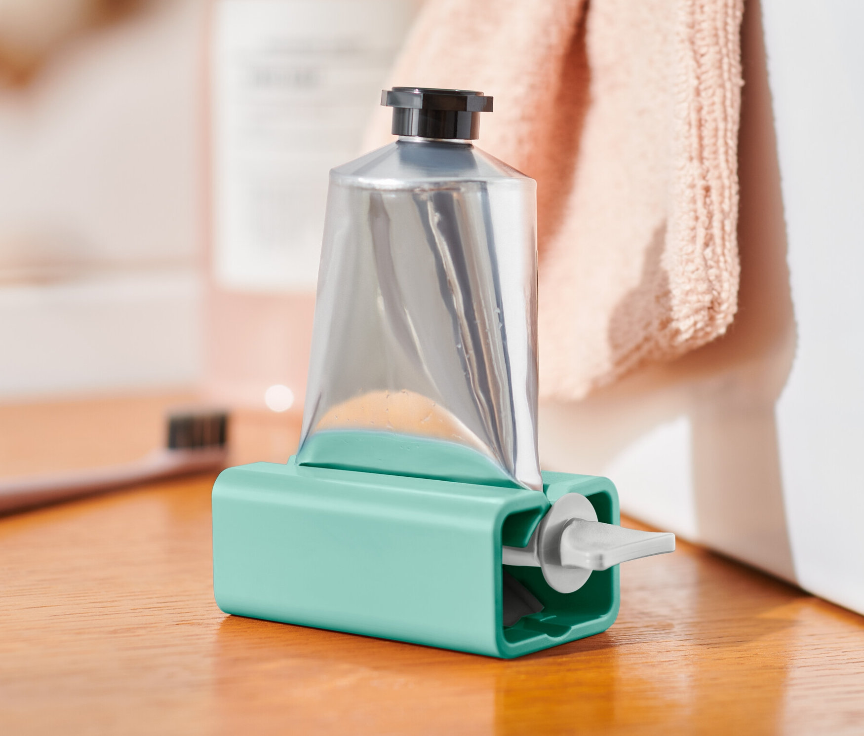 Tube argentée dans un presse-tube turquoise sur une armoire en bois.