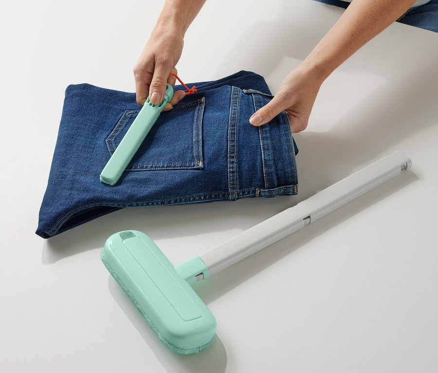 Une personne utilise un accessoire de nettoyage pour textiles 4 en 1 sur un jean plié.