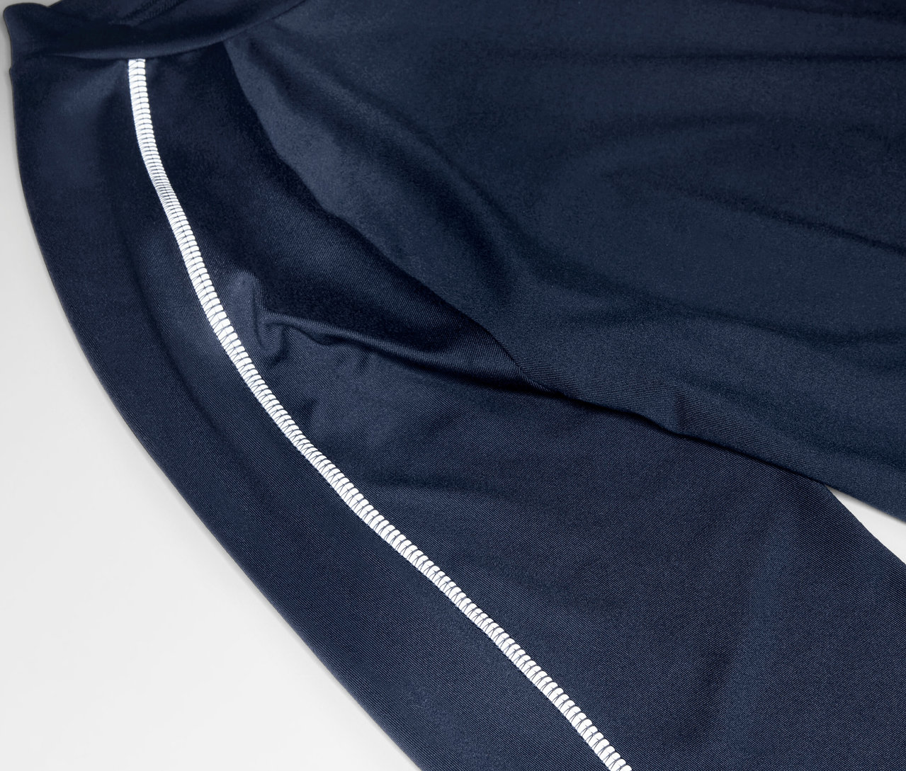 Gros plan sur un pantalon de survêtement bleu marine avec une bande blanche sur le côté.