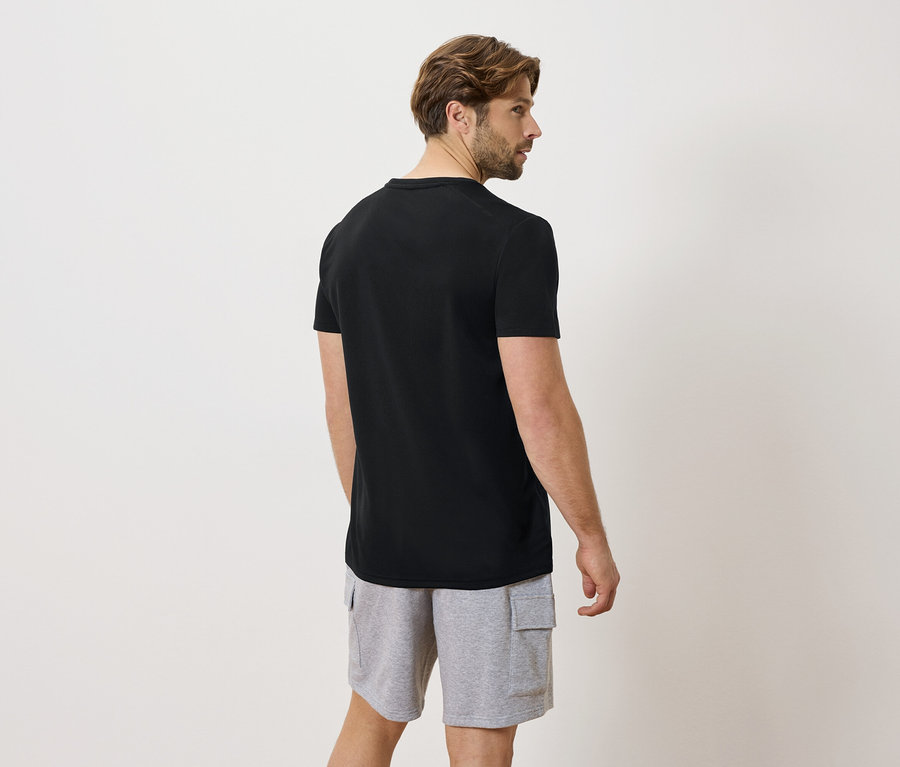 Homme de dos portant un t-shirt noir et un short gris