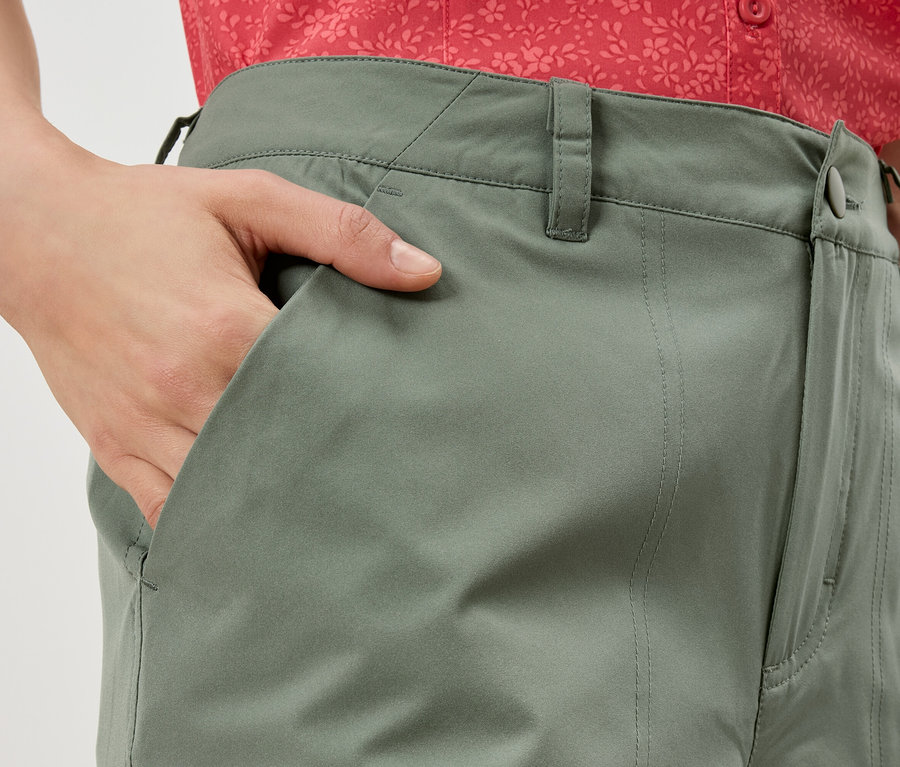 Gros plan d'une personne portant un pantalon vert olive et mettant sa main dans sa poche.