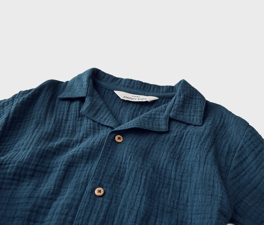 Gros plan d'une chemise bleu foncé avec un col et des boutons.