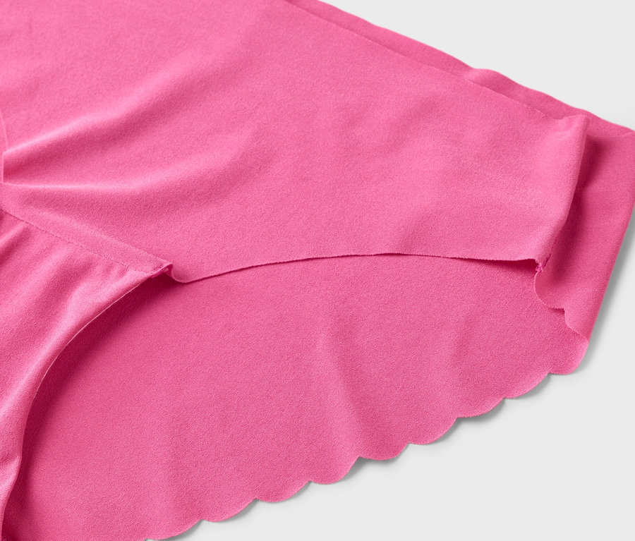 Gros plan d'une culotte rose avec un bord festonné sur fond blanc.