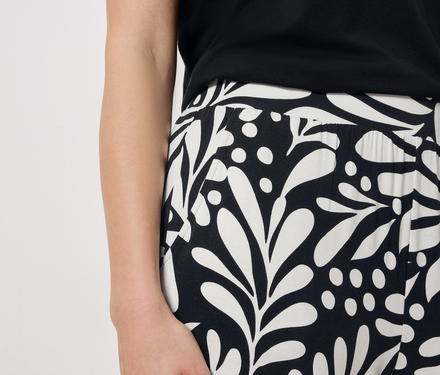 Gros plan d'une femme portant une robe à motifs noirs et blancs.