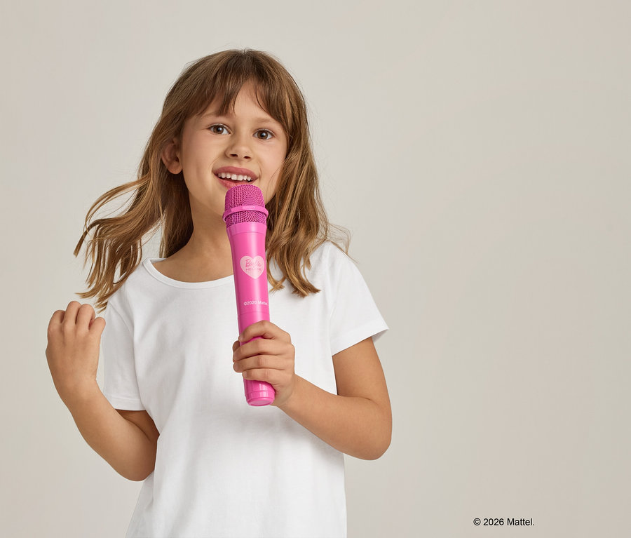 Fillette en t-shirt blanc tenant un microphone rose.
