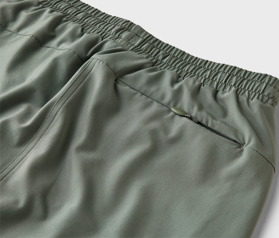 Gros plan d'un pantalon vert olive avec une taille élastique et une poche zippée.