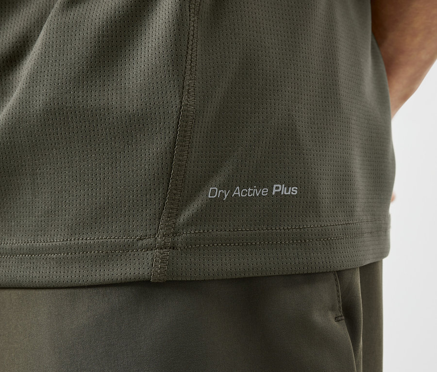 Gros plan d'un t-shirt de sport vert olive avec l'inscription "Dry Active Plus".