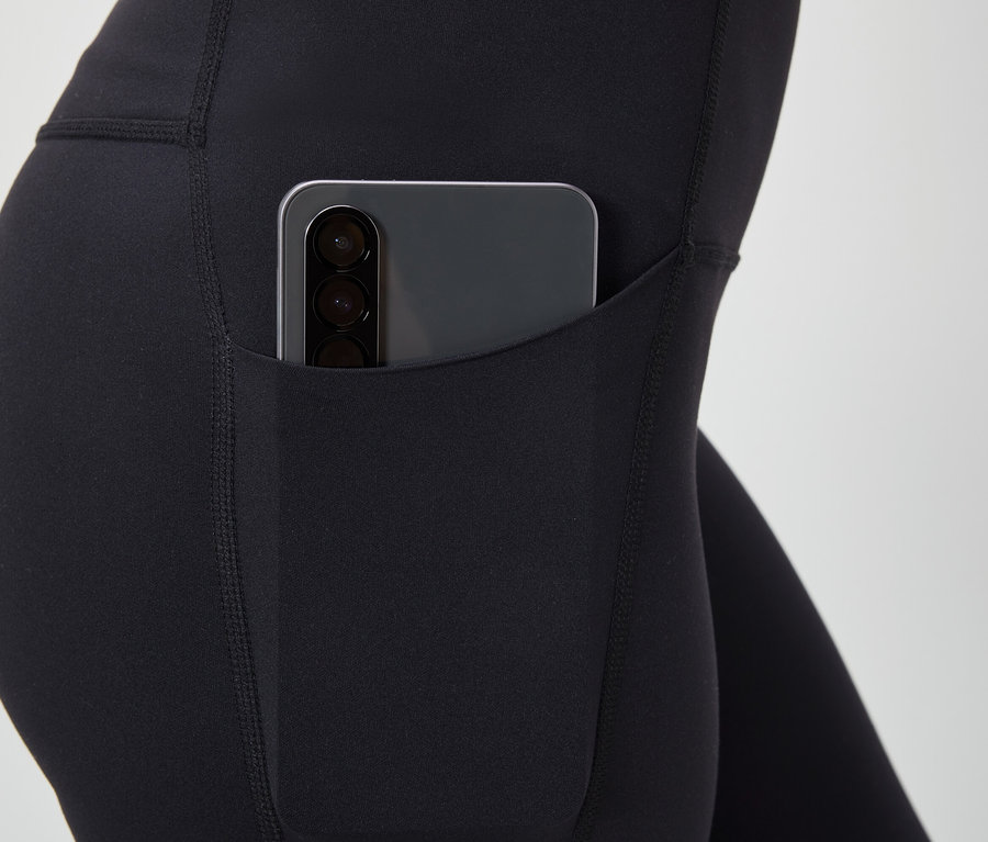 Vue détaillée d'un legging noir avec un smartphone dans la poche.
