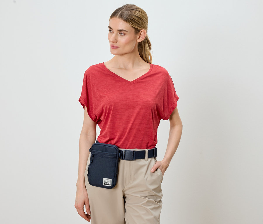 Femme portant un t-shirt rouge, un pantalon kaki et une sacoche de ceinture bleue.