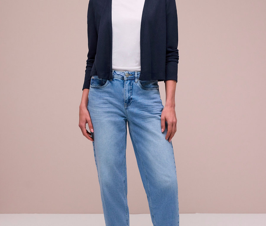 Femme portant un Cardigan Street One bleu foncé sur un t-shirt blanc, un jean bleu clair, un foulard à motifs et des baskets argentées.