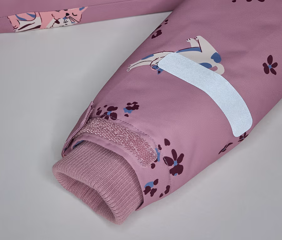 Gros plan sur une manche rose à motif de chat, une bande réfléchissante et un poignet côtelé.