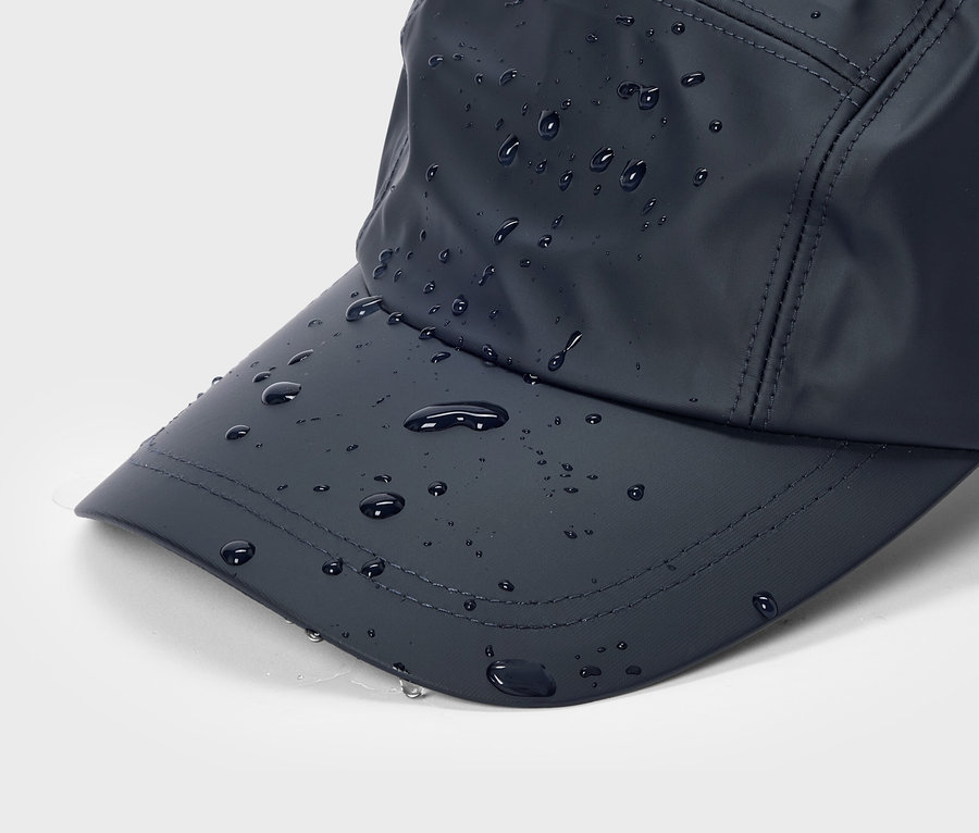 Gros plan d'une casquette de baseball bleu marine avec des gouttes d'eau sur la visière et le dessus.