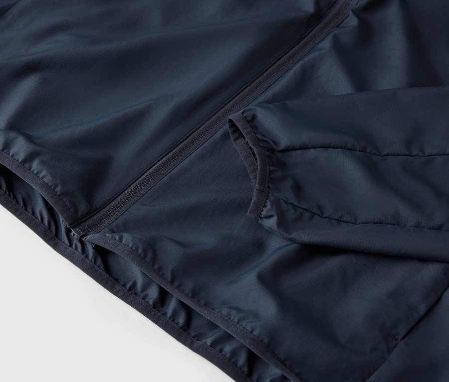 Gros plan d'une veste bleu marine avec fermeture éclair et poches.