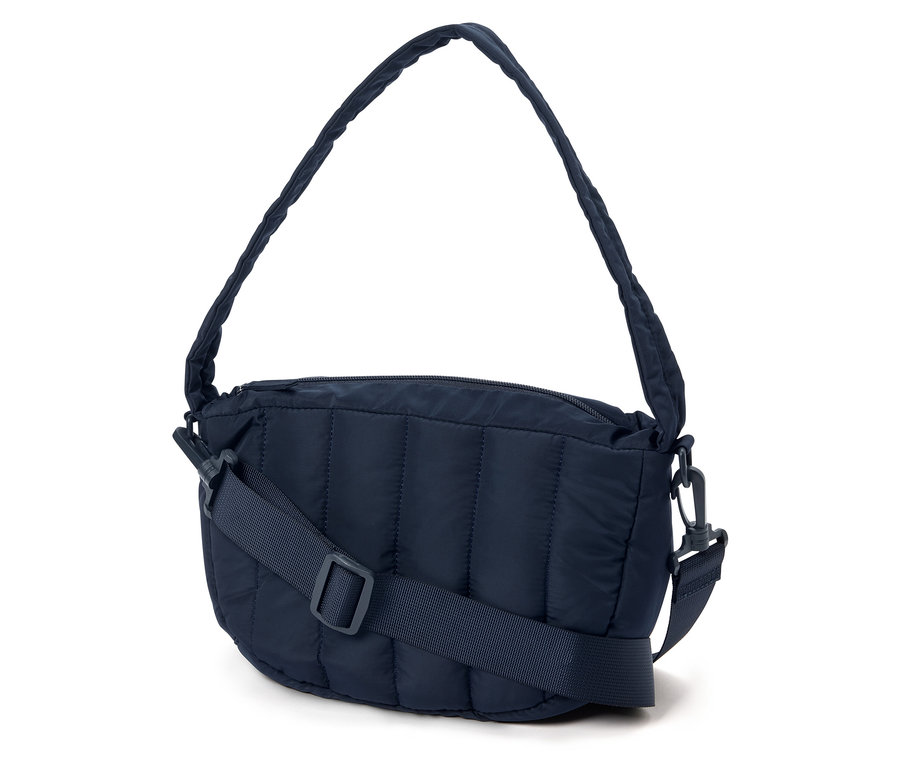 Un sac à main matelassé bleu marine avec une bandoulière réglable posé sur un fond blanc.