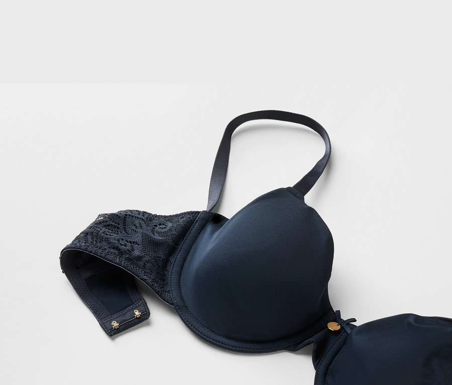 Gros plan d'un soutien-gorge bleu marine avec dentelle et armatures sur fond blanc.